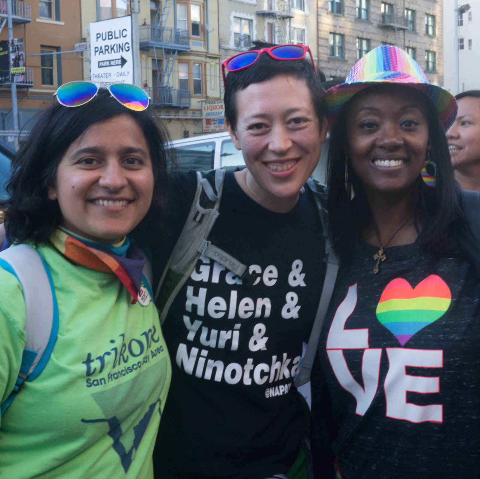 Image Description: Three queer people stand smiling towards the camera at the 2016 Trans March. 