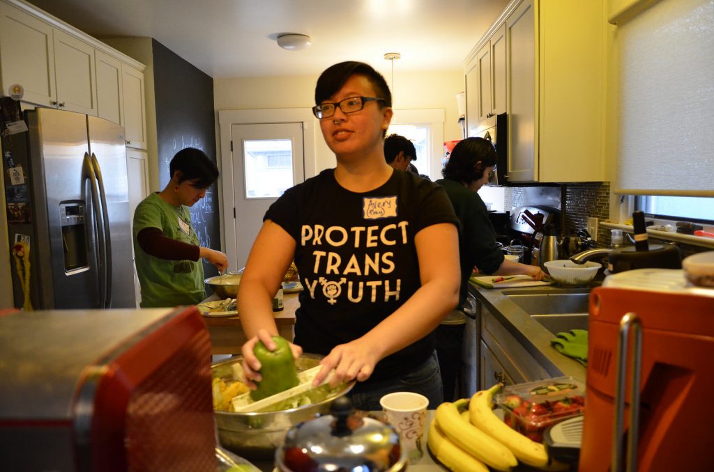 [Image Description: Brunch crew volunteer stands at kitchen counter, preparing ingredients]